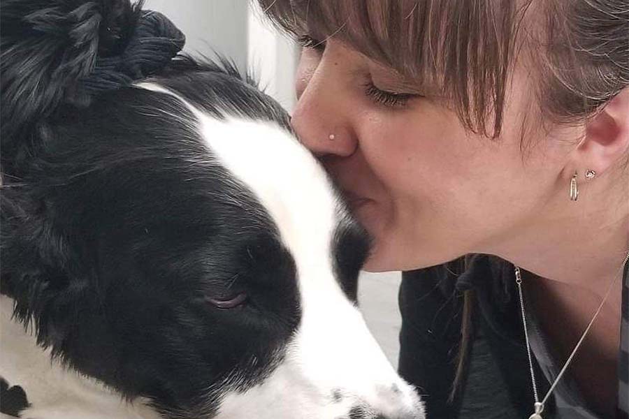 staff member gives dog a kiss